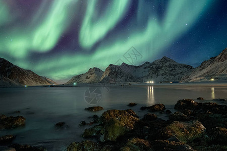 Auroranoramalis与在海岸线上山脉上的星相伴图片