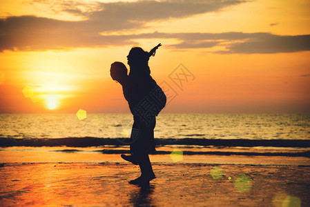 亚裔情侣在海滩上快乐的情侣在背景男人举起女人图片