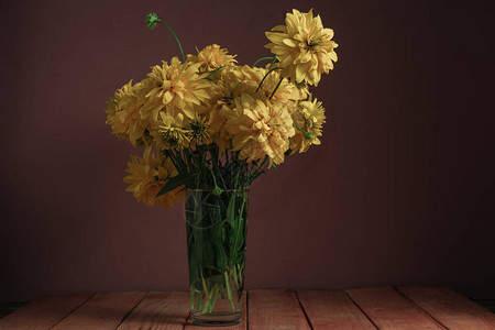红色木桌上的花瓶里的黄色花朵美丽图片