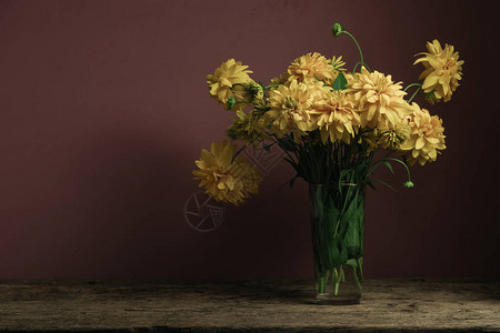 古老橡木桌上的花瓶里的黄色花朵美丽图片