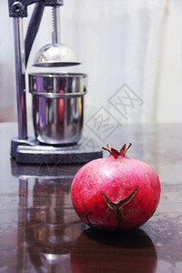 家庭室内的红石榴水果和金属手动榨汁机图片