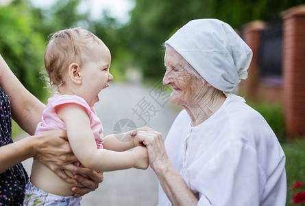 快乐的蹒跚学步的女孩和她的曾祖母手牵图片