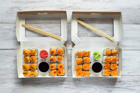 两条寿司放在木制桌上的盒子里图片