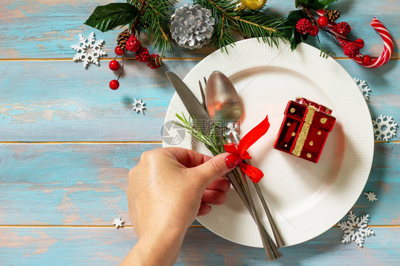 圣诞节背景圣诞装饰桌女手在复古木桌上供应节日餐桌白盘礼物和餐具图片