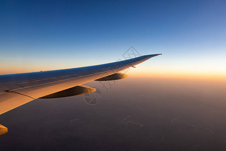 飞机翼在城市上空飞机在蓝天上飞行从飞机窗口的风景早上有阳光的商业航空公司飞行云层之上的平面机翼图片