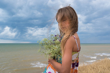 一个悲伤的女孩的肖像鲜花对着大海图片