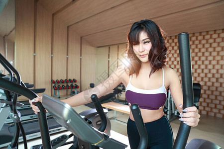 在健身房使用运动机的年轻健康和运动妇女肖像这是健身和锻炼图片