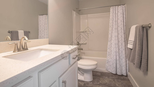 全景家庭浴室内部配有深灰色瓷砖地板和浅灰色墙壁房间配有梳妆台卫生间和带淋浴图片