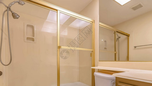 全景浴室内部配有水槽柜和大镜子下方的马桶浴缸和淋浴间设有带金色背景图片