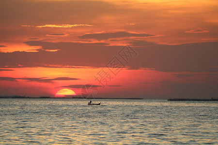 夕阳在红色的天空背晚云在地平线海和渔船图片