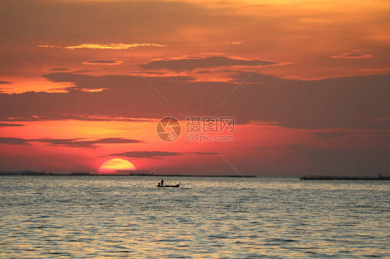 夕阳在红色的天空背晚云在地平线海和渔船图片