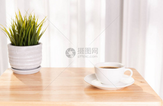 木质办公桌上的白色咖啡杯和植物盆图片