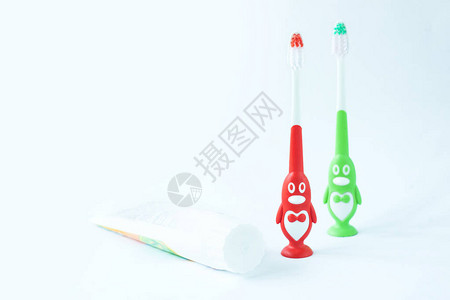 卫生间装修效果图红色和绿色企鹅形式的儿童牙刷和白色背景上的牙膏管儿童口腔护理第一乳牙卫生浴背景