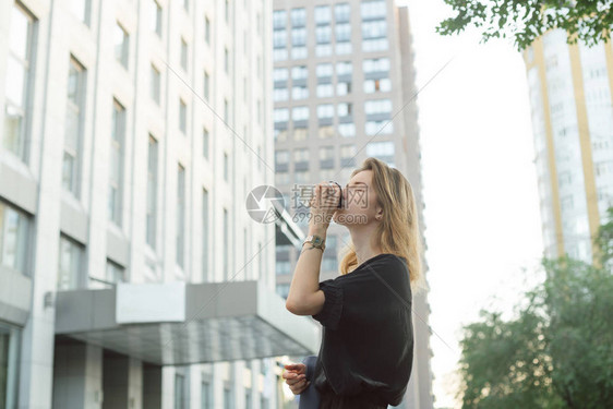 格开朗的时尚女商人在城市背景下在外面喝咖啡有魅力的年轻女人在办公楼和摩天大楼附近的街道上图片