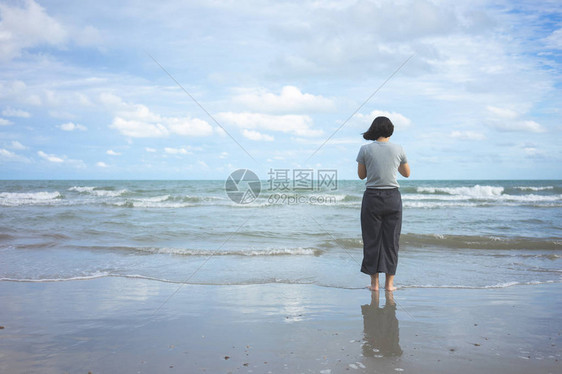 亚洲年轻女子面向大海站立图片