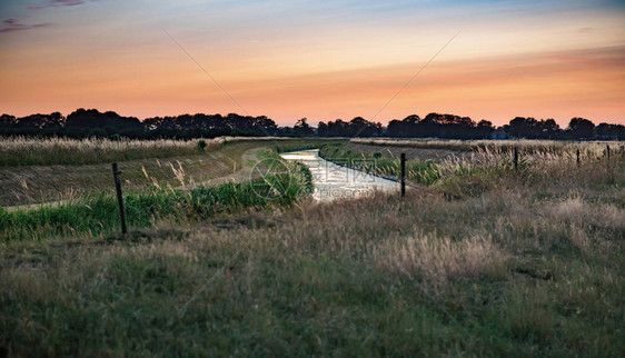 日落时穿过乡村景观的河流图片