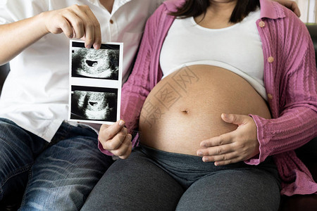 怀孕的夫妻在家里抱着婴儿照片感受爱和放松产妇和怀图片