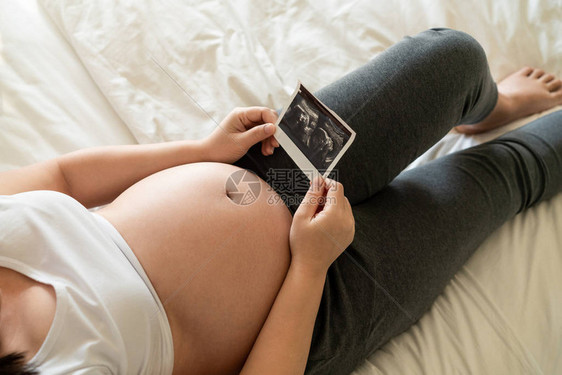 孕妇在照顾孩子的同时在家感到快乐年轻的准妈抱着在怀孕的肚子里产前护理和图片