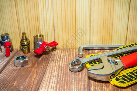 不同的管道用品和木制复古背景上的工具适用于水暖图片