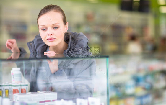 年轻女在现代药店寻找正确的药片处方浅体DOF图片