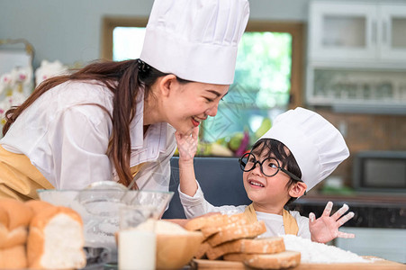 可爱的亚洲小男孩用面团粉画美丽的女人脸厨师团队在家庭厨房里玩耍和烘焙面包店很有趣自制食物和面包教育团队合图片