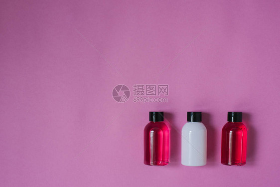 粉红色背景上用于化妆品淋浴胶洗发水和头发润滑剂的小旅行小瓶的顶部成分图片