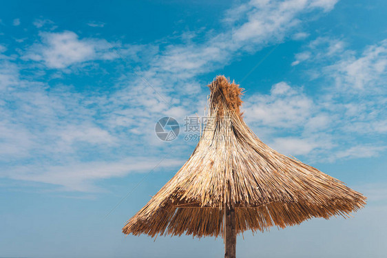 反对蓝天的稻草沙滩伞图片