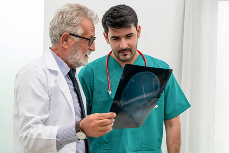 医院的医生与另一位外科医生一起研究病人头部的X光片医疗保健和医务图片
