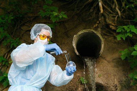 使用试管的女生物化学家或传染病专家在漏水管道的背景下对水图片