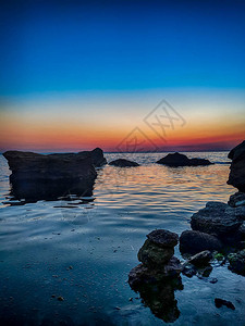 夏季日落时带石头的海线背景图片