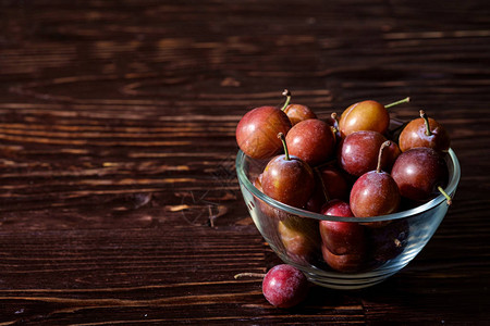 玻璃碗里成熟的甜李子水果背景图片