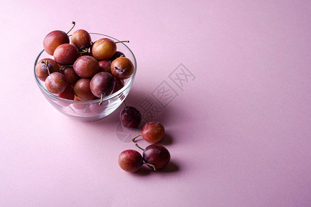 在靠近玻璃碗的玻璃碗中提取甜李子水果背景图片