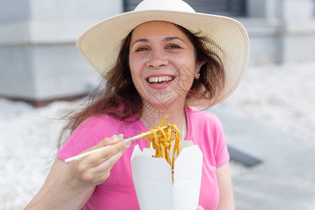 戴帽子的年轻正面女孩吃面条图片