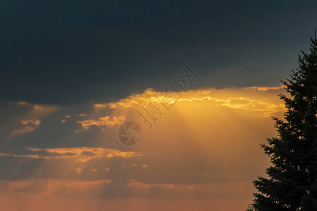 太阳的橙色光束穿透云层日落图片
