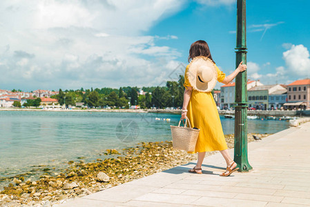 夏日穿着黄色吊带裙在海边散步的女人暑假图片