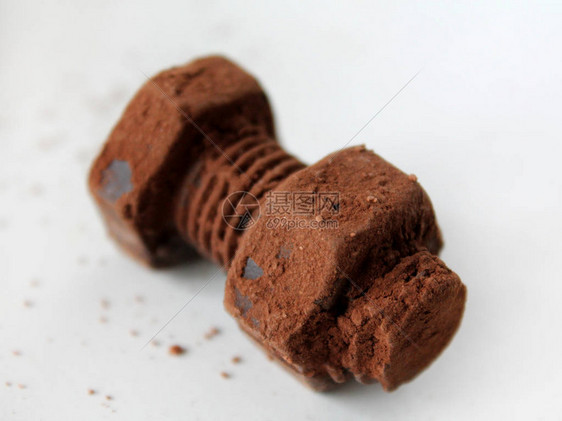 生锈的螺栓和螺母由孤立的白色背景上的巧克力制成巧克力片散落在光滑的表面上机械传动背景父图片