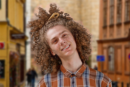 一个卷发的年轻人的肖像满头发的木梳子在街上微笑图片