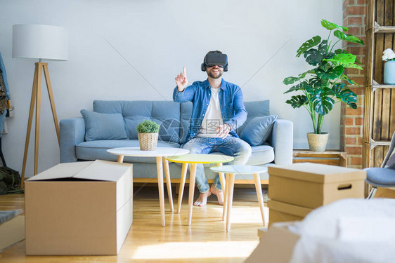 戴着虚拟现实眼镜的年轻人坐在沙发上玩模拟游戏图片
