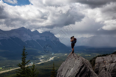 冒险的女孩在多云和雨天在落基山顶拍照取自加拿大艾伯塔省坎莫尔的麦图片