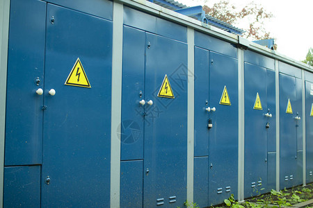 蓝色变压器箱变电站蓝色墙上带有注意标志的锁定电动金属背景图片