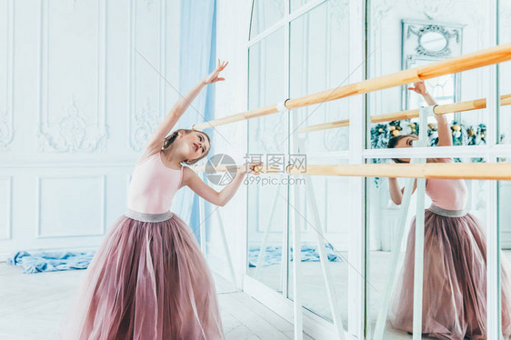 舞蹈课上的年轻古典芭蕾舞演员女孩美丽优雅的芭蕾舞女演员在白光大厅的大镜子附近穿着粉色短裙图片