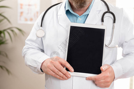 男医生在医生办公室或医院的平板电脑上显示数字图像或报告医疗图片