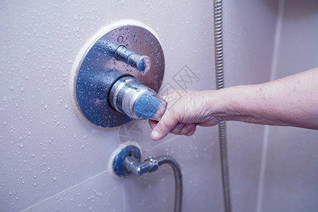 亚洲老年或老年妇人患者在护理医院病房使用厕所浴室打开淋浴图片