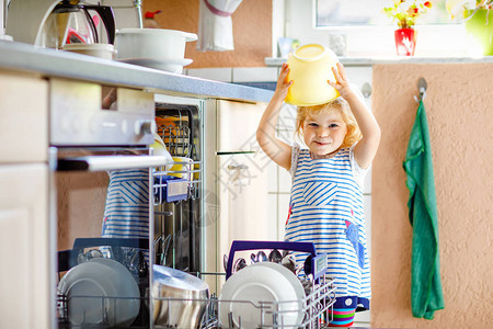小可爱蹒跚学步的女孩帮助卸载洗碗机图片