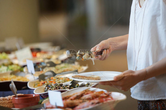 从自助餐线上拿食物的女人图片