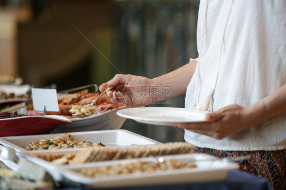 从自助餐线上拿食物的女人图片