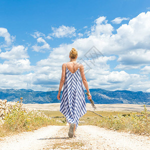 穿着夏装的女人在克罗地亚帕格岛上穿过干燥的岩石地中海岸景观时图片