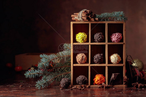巧克力糖果装在木盒和圣诞装饰品中巧克力肉桂棒香肠和咖啡豆的碎图片