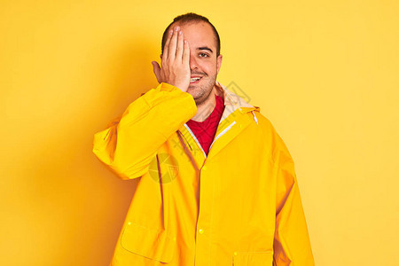 身穿雨衣的年轻人站在孤立的黄色背景上图片