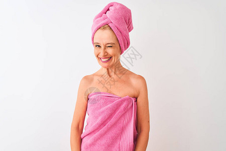 中年妇女洗完澡后穿着浴巾站在孤立的白色背景上眨着眼看着镜头图片